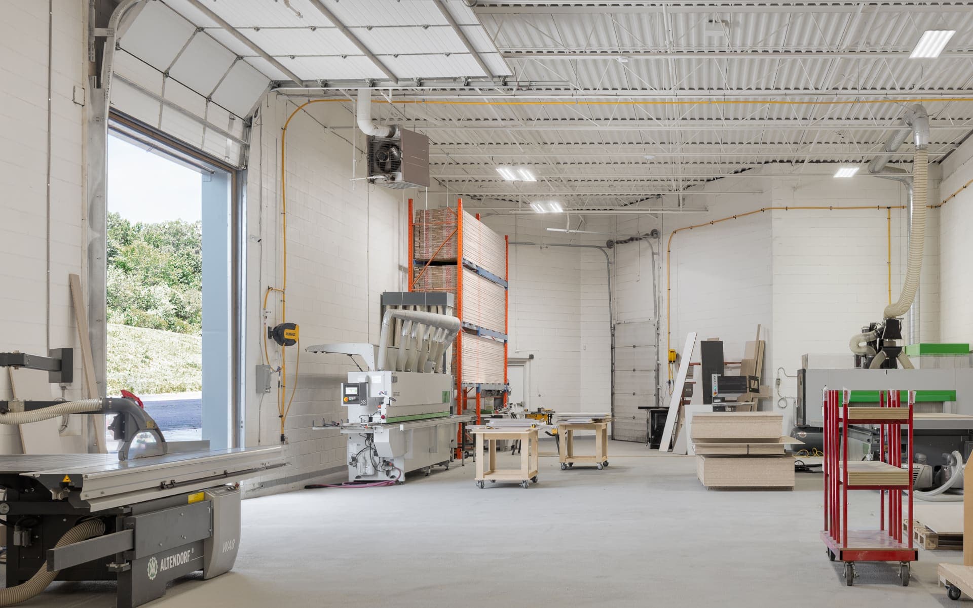 The Cabintie production floor, with a panel saw, edgebander, and stacked sheet stock
